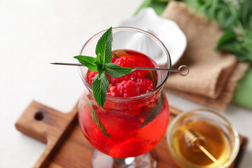 Glass of fresh raspberry lemonade and bowl with honey on white background