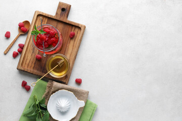 Glass of fresh raspberry lemonade and bowl with honey on white background