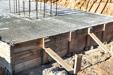 Monolithic reinforced concrete foundation for the construction of a residential building. Grillage on a construction site with wooden formwork. Construction pit with foundation.