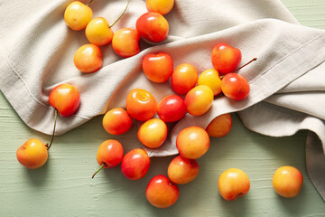 Many sweet yellow cherries on green wooden background