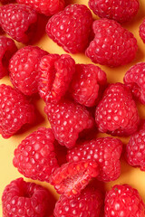 Many fresh raspberries on yellow background