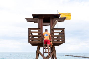 Lifeguard climbing a control tower next to the sea
