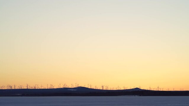 Markbygden Windmill park in the distance with Wind Turbines in motion rotating generating green electricity at sundown on a hill outside of Pitea, Northern Sweden. 