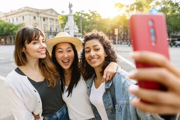 Young diverse female friends enjoying summer days taking selfie together outdoors. Three beautiful...