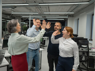 Obraz premium Four co-workers give a high five in the office.