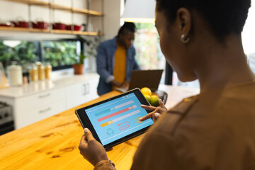 African american woman using tablet with smart home interface in kitchen
