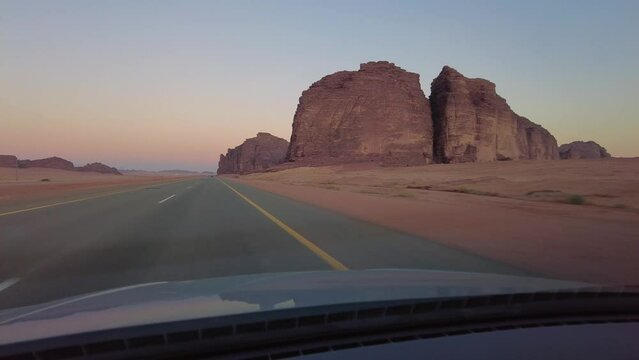 Tabuk, Saudi Arabia: Point of view of a car driving on the stunning red desert out of Tabuk in northwest Saudi Arabia in the middle east at sunset. 