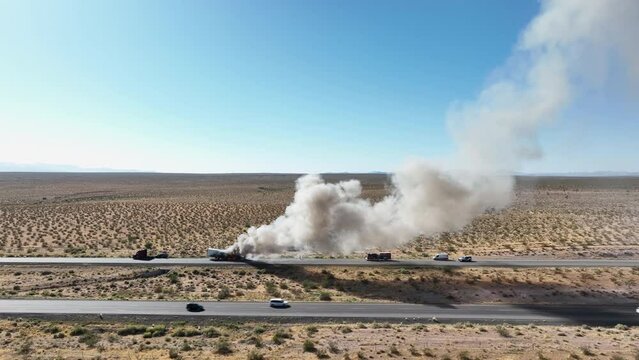 Aerial semi truck trailer fire desert highway forward. Interstate highway in desert of Arizona and Nevada. Transporting fresh meat. Fire and smoke destroys cargo and HAZMAT pollution.