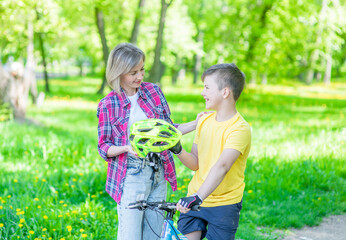 Naklejka na ściany i meble Activity family leisure. Mom gives her son a helmet for a safe ride on a bike