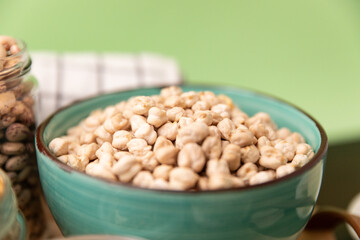 bowl full of chickpeas on wooden table with green background. Top view.
