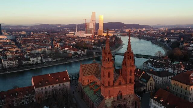 Basel, Switzerland: Aerial drone footage of Basel medieval old town along the Rhine river at sunset with a modern skyscraper, from a pharma company in the background in Switzerland. 