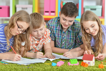 Fototapeta premium Children lying on floor drawing with pencils