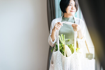 Woman holding mesh shopping bag with fresh vegetables,No plastic bag,Zero waste,Environmental friendly,Healthy green