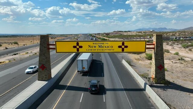 New Mexico welcome sign above highway. Aerial dolly forward towards establishing sign of NM.
