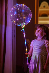 Little Girl with Illuminated Balloon at Night. Excited Preschool Child Looking at Lights Inside the Balloon.