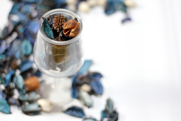 A mix of dry flowers, leaves, petals, and other plant parts. Potpourri background. Purple and blue tone leaves, white color and wood grain background shot.