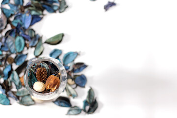 A mix of dry flowers, leaves, petals, and other plant parts. Potpourri background. Purple and blue tone leaves, white color and wood grain background shot.