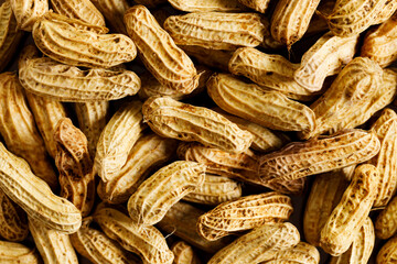 Unpeeled and peeled groundnuts on brown color background.