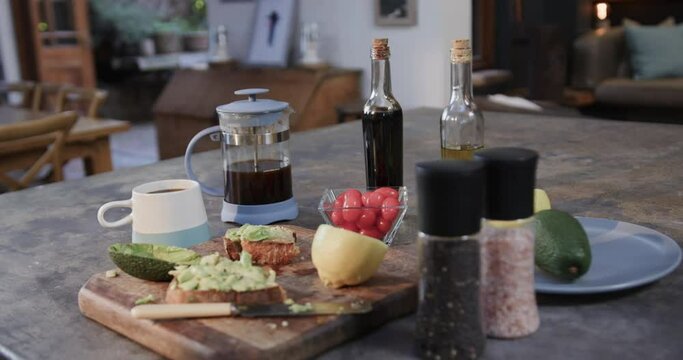 Close up of avocado sandwiches, vegetables, spices and coffee in kitchen, slow motion