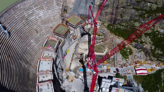 Aerial drone top down shot over a dam under construction in Grimsel Pass, Swiss Mountain, Switzerland on a sunny day. Rotating shot.