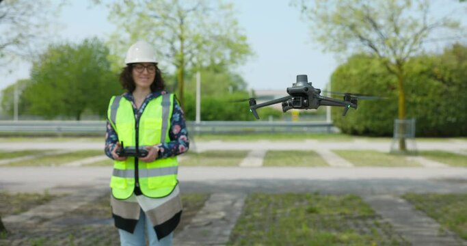 Female Surveyor Operating Professional Aerial Drone In Car Park Wearing Hi Vis