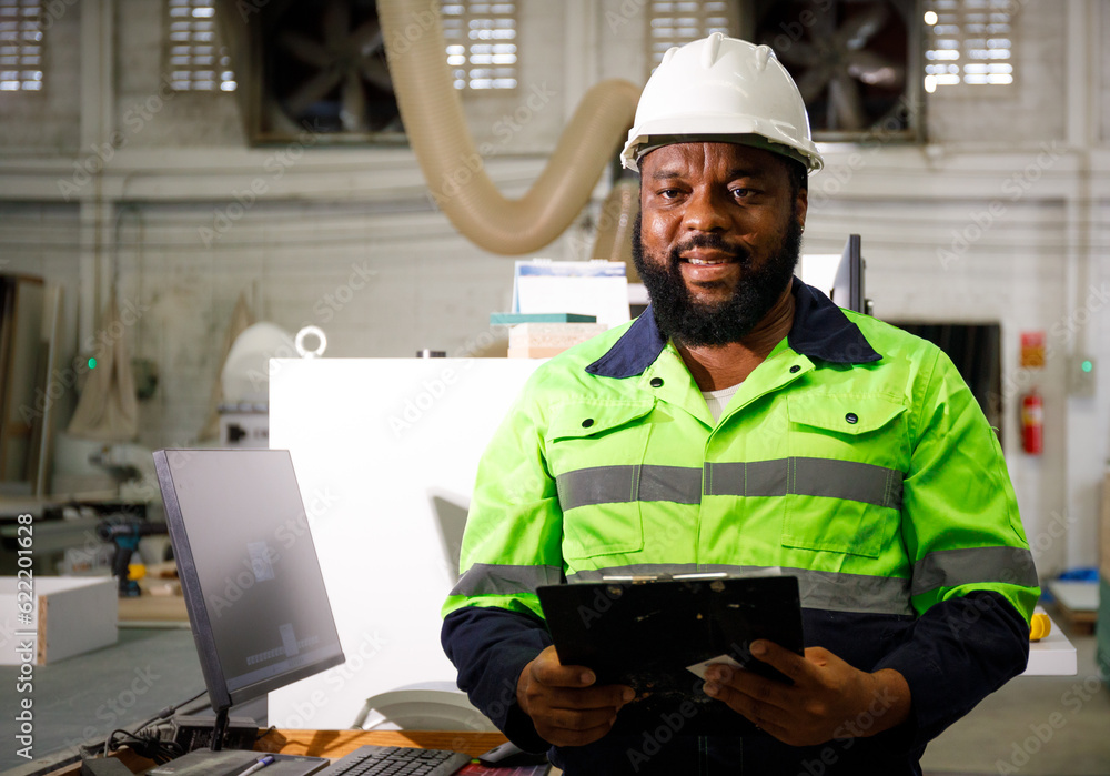 Poster portrait. african male engineer using a tablet computer. the background is a cnc cutting machine in 