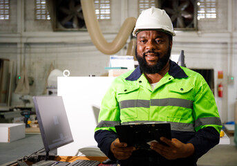 Portrait. African male engineer using a tablet computer. The background is a CNC cutting machine in the factory.