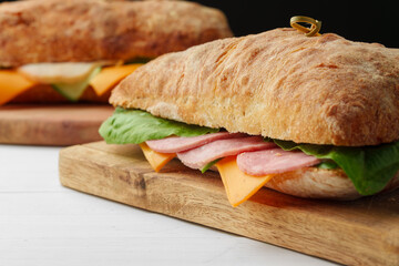 Chiabatta sandwich with ham and cheese on wooden board