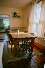 Room with wooden floor and dining table by a window.