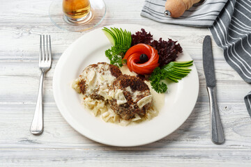 Two beef patties with sauce and fresh vegetables served on plate in cafe