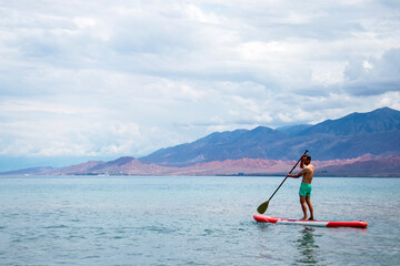 Fototapeta na wymiar A man on a surfboard with a paddle