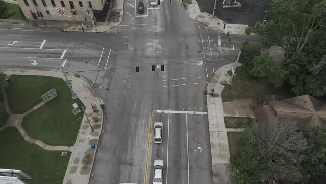 Intersection in downtown Elkhart, Indiana with truck and RV turning corner with stable drone video.