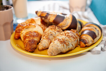 Chocolate croissants or croissant with nut crumbs on a plate. Delicious breakfast on the table. Tasty sweet baking dessert for coffee. Food background. Fresh buttery croissants rolls