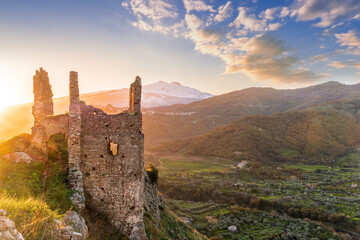 Fototapeta premium beautiful sunset or sunrise landscape of ancient ruins on a top of a hill with green mountains with white snow top on background