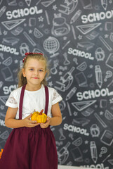Cute first grader holding a pumpkin in her hands. Children. Elementary school. Education concept.