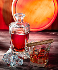 A glass of scotch whiskey with ice and a cigar on a wooden table close-up.