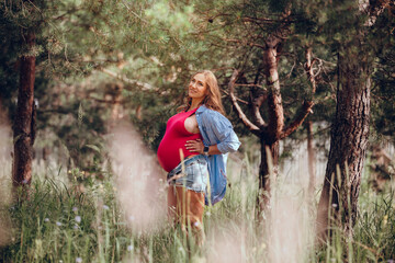 Beautiful pregnant woman a enjoys a walk in the forest. Outside relaxing, peace of inspiration in the dream birth of a child