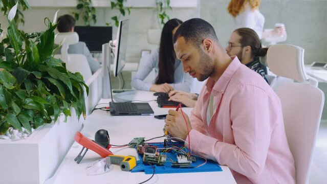 Multi Ethnic Serious Male Worker Measuring Voltage Using Multimeter.