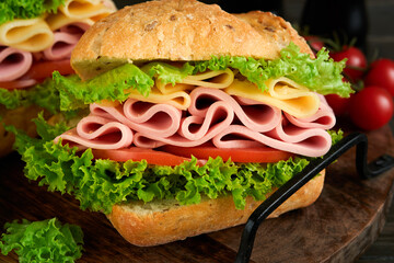 Sandwich. Tasty sandwich with ham or bacon, cheese, tomatoes, lettuce and grain bread on dark backgrounds. Delicious club sandwich or school lunch, breakfast or snack.