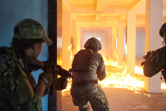  A group of professional soldiers bravely executes a dangerous rescue mission, surrounded by fire in a perilous building.