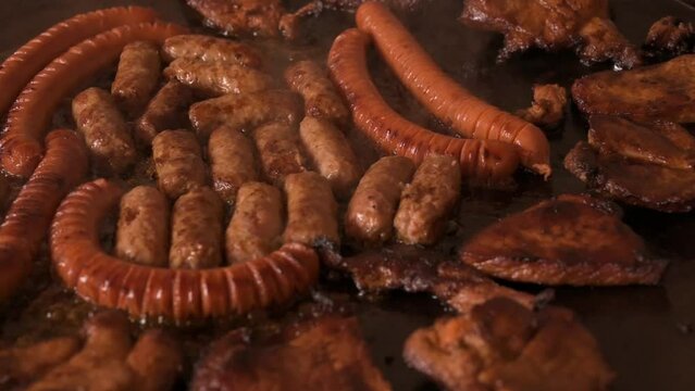 Sausages,  cevapi and chuck meat in a frying pan -  slow motion