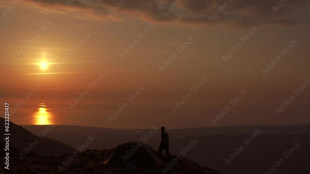 Wall mural A man wandering around a mountain summit at sunset