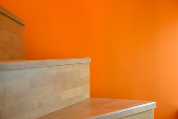 wooden stairs against an orange wall background, creating a visually striking contrast between natural and vibrant elements. - 622223616