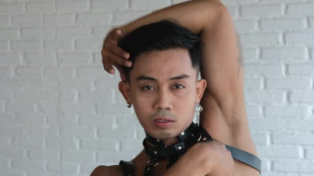Face close-up Attractive Asian homosexual demonstrates poses from Vogue. A transgender model poses in front of a lens for a fashion magazine for the gay and LGBT community. Diversity of man as person.
