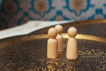 wooden figurines of people on the table. subject photo session of humanoid toys in the room. wooden toys on a bronze plate