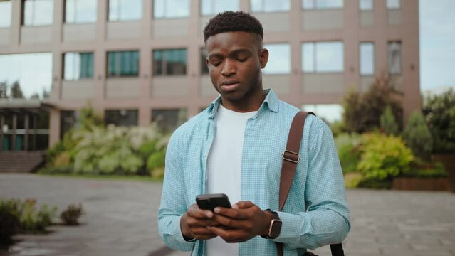 Young man looks at mobile phone with sad expression