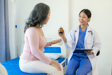 Obraz premium Young Asian nurse caregiver with 60 year old Asian woman giving advice and encouragement Take a history and recommend appropriate treatment to live happily in retirement in the clinic.