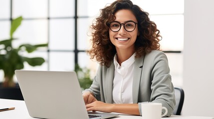 Smiling female professional executive using computer in corporate office looking at camera - obrazy, fototapety, plakaty
