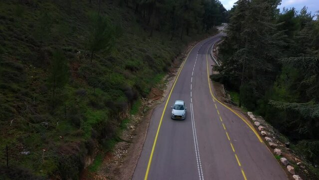 Aerial: Drone Flying Over Cars On Road Amidst Green Plants And Trees - Safed, Israel