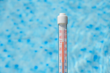 Termometr pokazujący wysoką temperaturę na tle basenu ogrodowego - obrazy, fototapety, plakaty